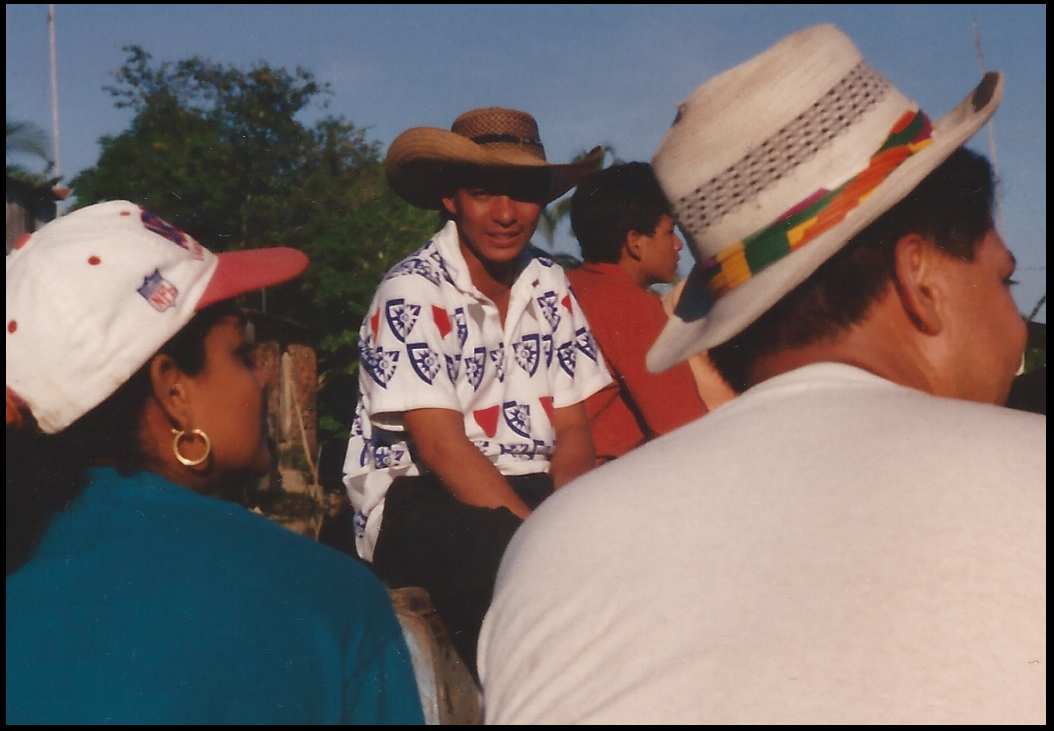 young man half-smiling from the shadow of his Colombian
            peasant straw hat brim