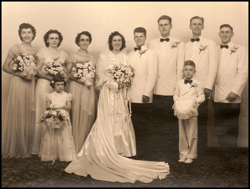 black and white professional photo of
              a 1950 wedding party with flower girl and little boy ring
              bearer