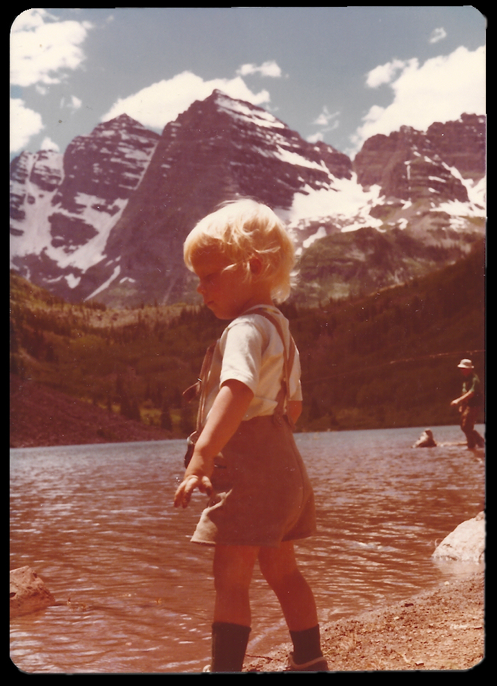 blond 3-year-old boy in
              foreground, Maroon Lake with fisherman, and Colorado's
              famous 'Maroon Bells', 2 similarly shaped mountains
              huddled like 2 bells
