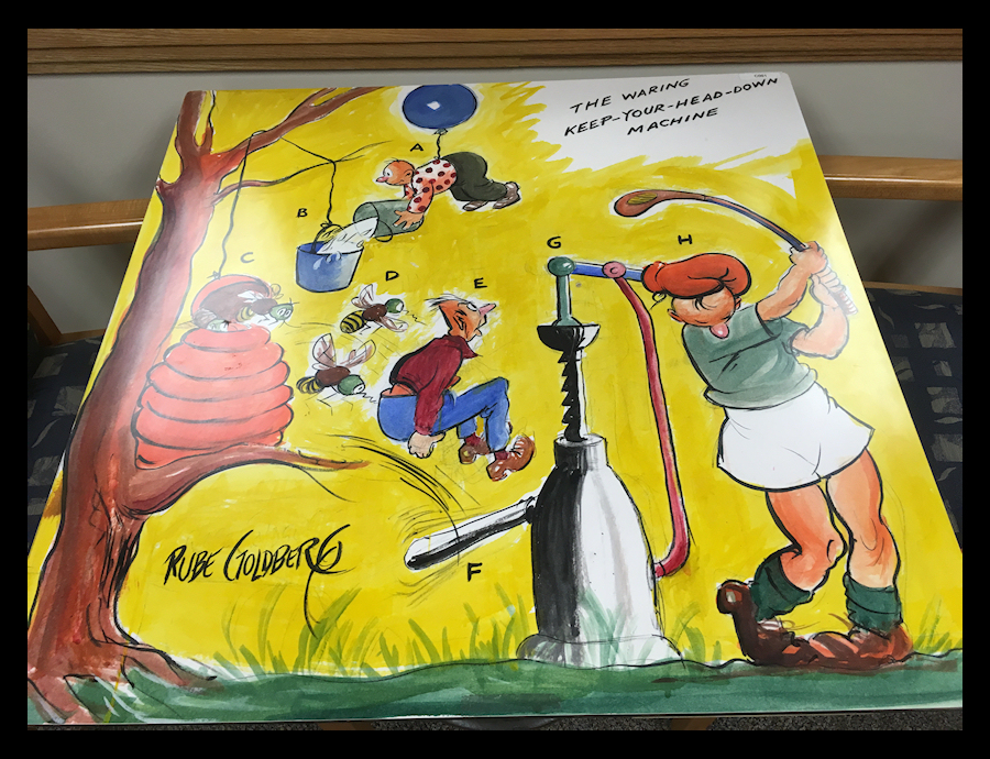 color tabletop cartoon by Rube
              Goldberg of a fantasy contraption for keeping your head
              down while golfing, named jokingly for Fred Waring