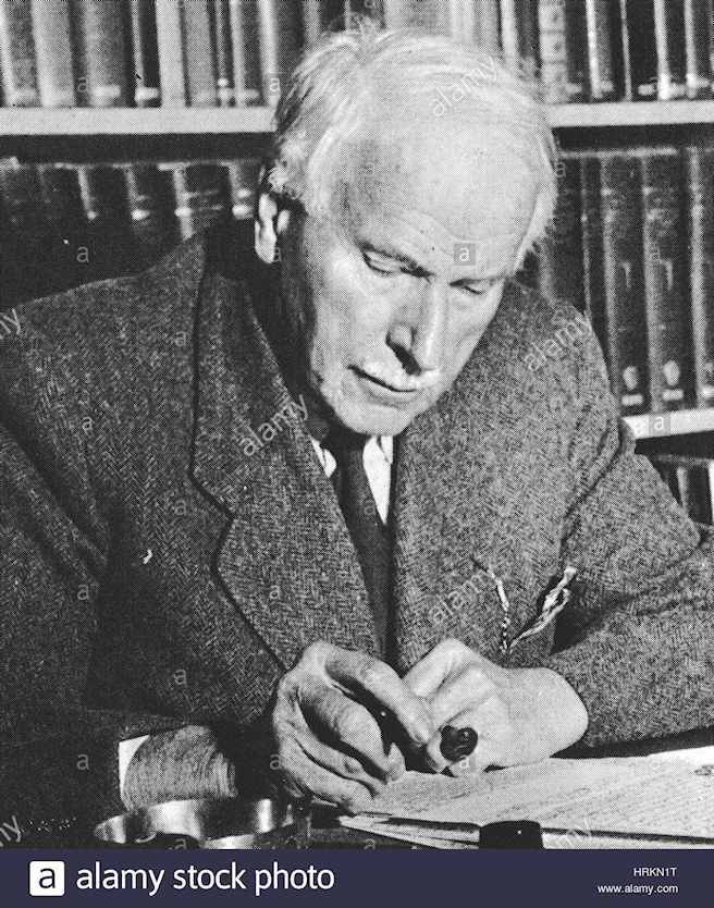 elderly, white-haired Jung in wool tweed
              jacket with pipe at his desk before shelves laden with
              books, black and white photo