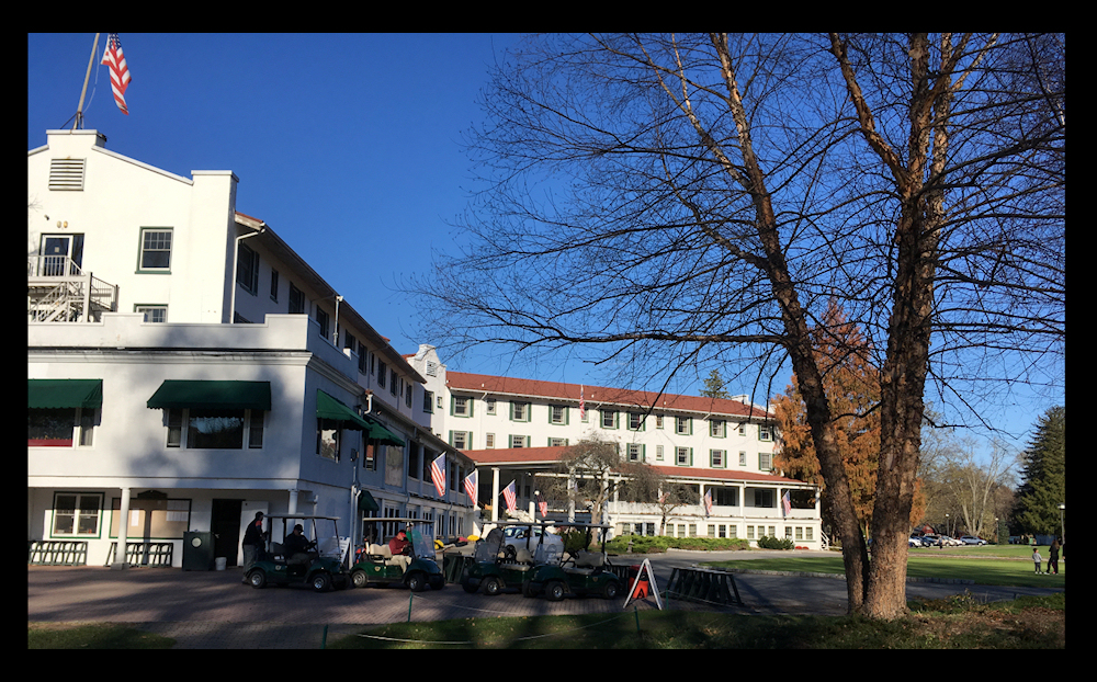 well-cared-for,
              3-winged, 4-story white inn with red roof and golf carts