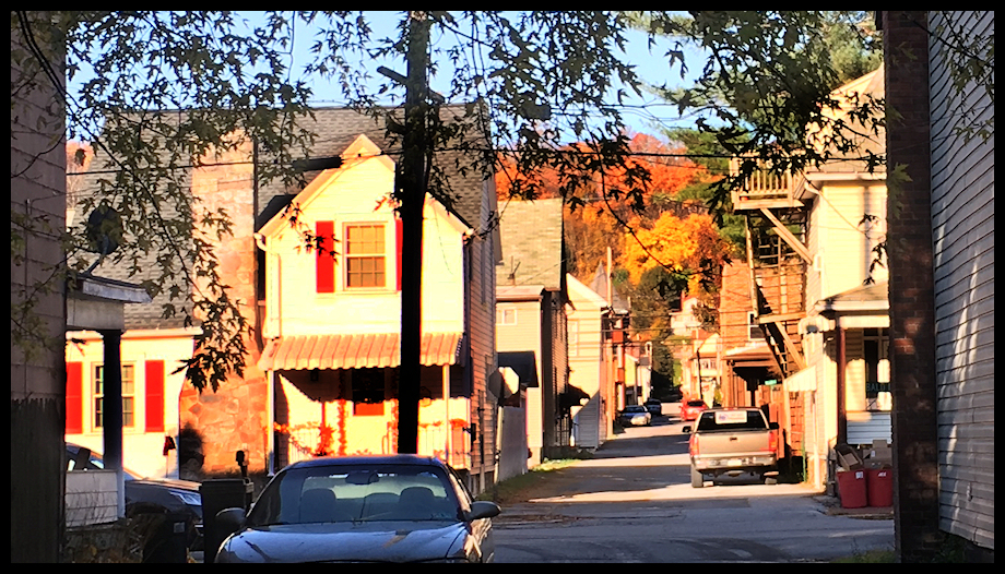 tall early 20th
              century houses packed in around an alley in Tyrone, Pa.,
              Fred Waring's birth town, caught in early morning sunlight
              in fall, with tree color