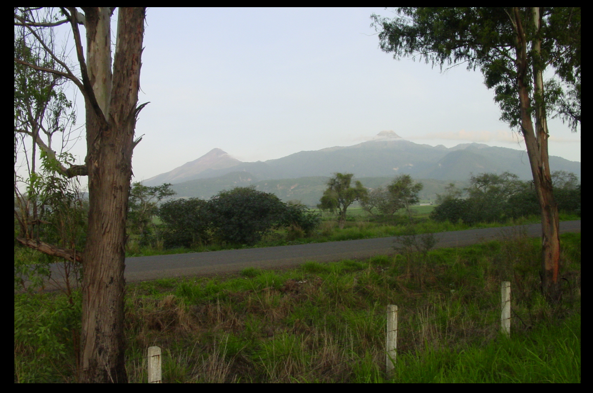 two high peaks grace a lovely
            green valley, highway in foreground