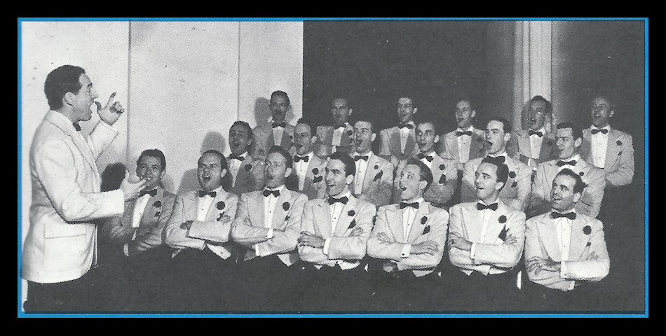 19 men seated with arms folded
          identically, all formally dressed identically with dark
          bowtie, boutonniere and pocket hanky, singing to Fred Waring's
          direction
