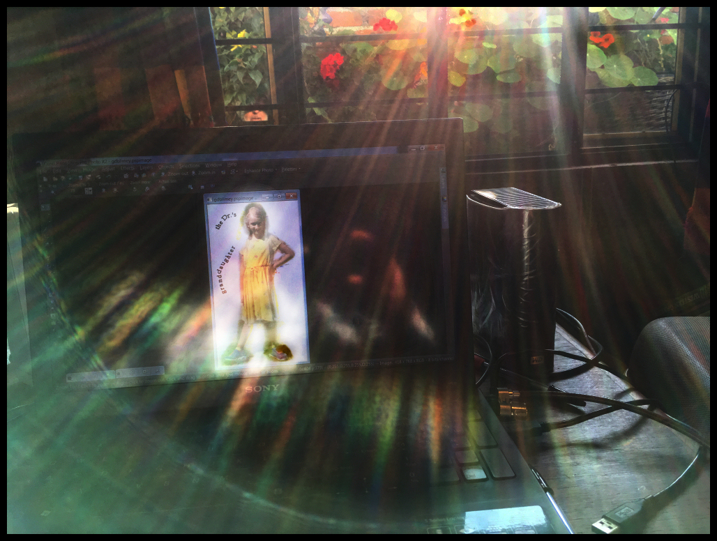 light
                  from the Dr.'s Mexican patio garden is filtered into
                  rainbow rays around a photo of his granddaughter he is
                  doctoring on his laptop, while he, with camera, is
                  reflected in the laptop screen